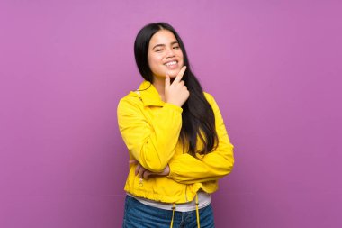 Genç Asyalı kız, izole edilmiş mor arka planda gülümsüyor