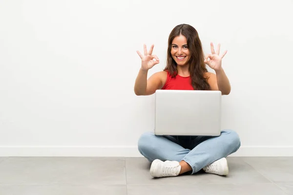 Dizüstü Bilgisayarı Olan Genç Bir Kadın Yerde Oturmuş Parmaklarıyla Tamam — Stok fotoğraf