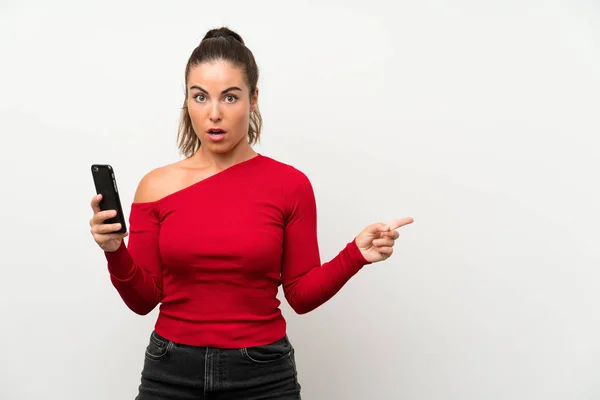 Young Woman Using Mobile Phone Surprised Pointing Side — Stock Photo, Image