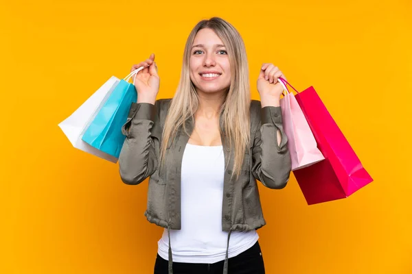 Young Blonde Woman Isolated Yellow Background Holding Shopping Bags Smiling — 스톡 사진