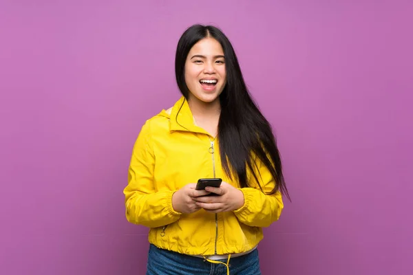 stock image Young teenager Asian girl over isolated purple background surprised and sending a message