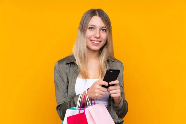 Young Blonde Woman Isolated Yellow Background Holding Shopping Bags Writing — 스톡 사진