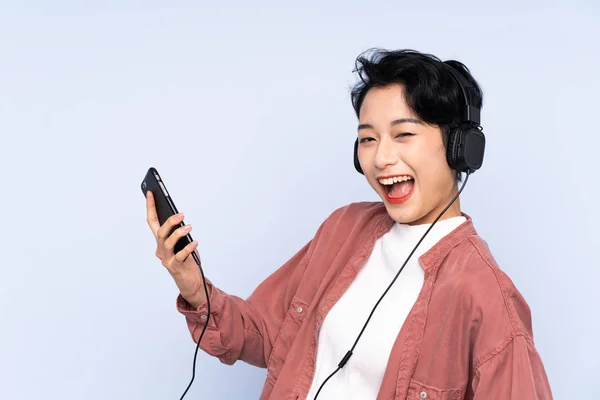 Joven Chica Asiática Sobre Fondo Azul Aislado Escuchando Música Haciendo — Foto de Stock