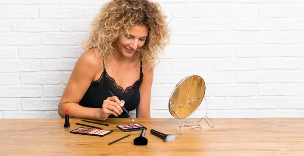 Jeune femme avec beaucoup de brosse de maquillage dans une table — Photo