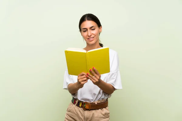 Молодая Женщина Изолированном Зеленом Фоне Держит Читает Книгу — стоковое фото