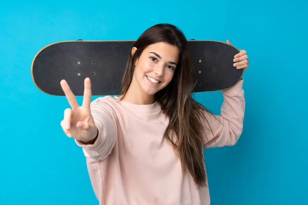 Tiener Meisje Geïsoleerde Blauwe Achtergrond Met Een Skate Doen Overwinning — Stockfoto