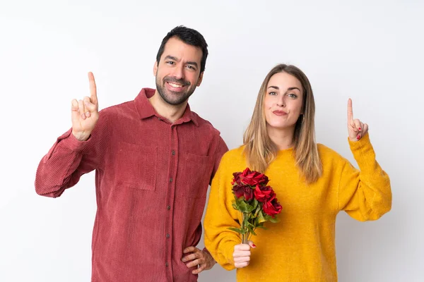 情人节的情侣们抱着鲜花在孤零零的背景上 举手表决 表示他们是最棒的 — 图库照片