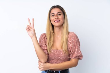 Genç Uruguaylı kadın izole edilmiş beyaz arka planda gülümsüyor ve zafer işareti gösteriyor.