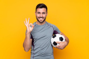 İzole edilmiş arka planda bulunan futbolcu, tamam işareti parmaklarıyla gösteriyor