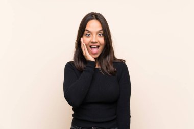 Beyaz kazaklı, esmer bir kadın. Arka planda, şaşırmış ve şok olmuş bir yüz ifadesi var.