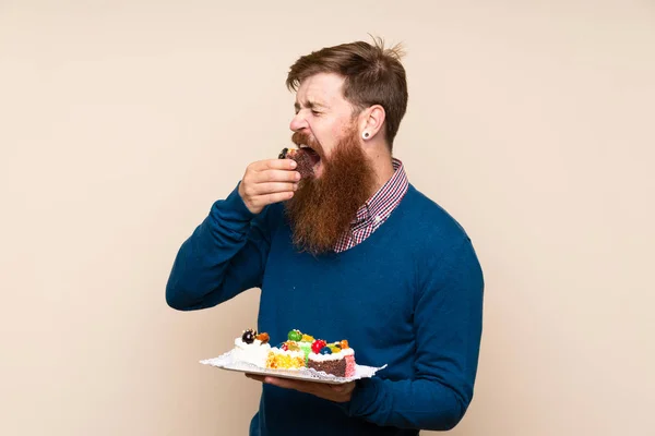 Roodharige Man Met Lange Baard Geïsoleerde Achtergrond Houden Mini Cakes — Stockfoto