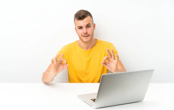 Masada Dizüstü Bilgisayarı Olan Genç Sarışın Adam Parmaklarıyla Tamam Işareti — Stok fotoğraf