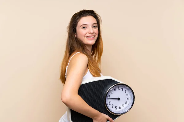 Young brunette girl  with weighing machine over isolated backgro — 스톡 사진