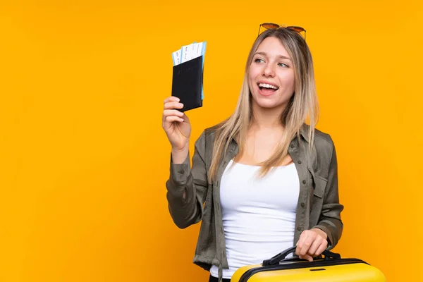 若いですブロンド女性以上隔離された黄色の背景で休暇とともにスーツケースとパスポート — ストック写真