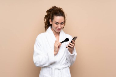 Makyaj paletli bornozlu genç bir kadın izole edilmiş arka planda.