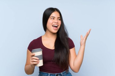 Genç Asyalı kız elinde sürpriz bir yüz ifadesiyle kahve tutuyor.