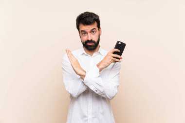 Elinde cep telefonu olan sakallı genç bir adam jest yapmıyor.