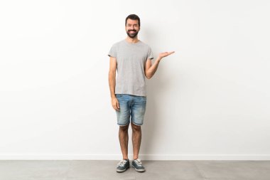 Tam boy, sakallı yakışıklı bir adamın, bir ilan vermek için avucunda hayali bir fotokopi makinesi tutarken.