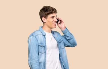 Yakışıklı genç adam izole edilmiş arka planda cep telefonuyla sohbet ediyor.
