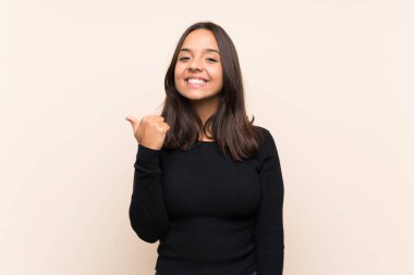 Bir ürün sunmak için yan işaret izole arka plan üzerinde beyaz kazak ile genç esmer kadın