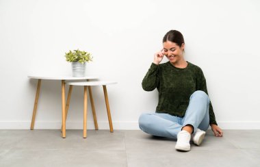 Genç bayan yerde oturmuş gülüyor.