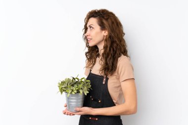 Genç, güzel bir kadın, izole bir arka planda saksı alıyor.