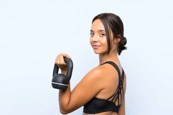 Ung sport Girl Making tyngdlyftning med Kettlebell över isolerad blå bakgrund — Stockfoto