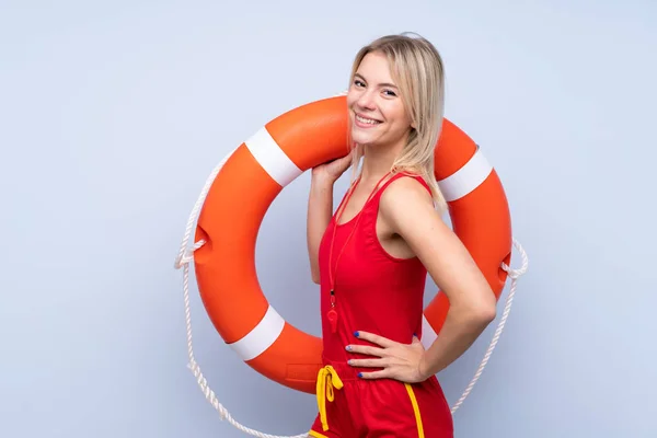 Lifeguard woman over isolated blue background with lifeguard equipment and with happy expression