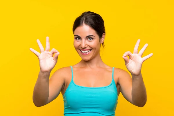 Junge Frau Auf Gelbem Hintergrund Zeigt Ein Zeichen Mit Fingern — Stockfoto