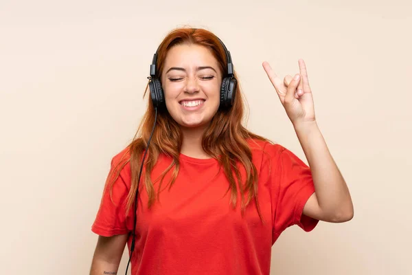 Nastolatek rudowłosy dziewczyna słuchanie muzyki na białym tle — Zdjęcie stockowe