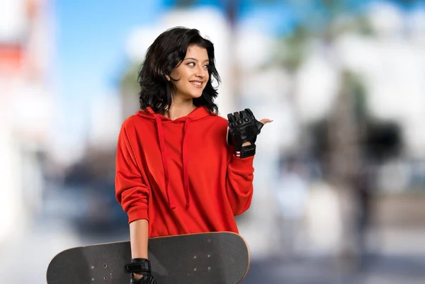 Młoda Kobieta Skater Wskazując Bok Aby Przedstawić Produkt Zewnątrz — Zdjęcie stockowe