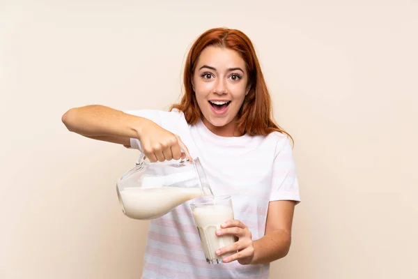 Adolescente pelirroja sosteniendo un vaso de leche sobre un fondo aislado — Foto de Stock