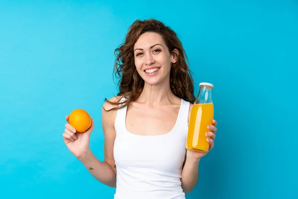 Ung Kvinna Med Lockigt Hår Håller Orange Över Isolerad Blå — Stockfoto