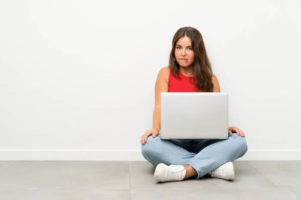 Junge Frau Mit Laptop Auf Dem Boden Sitzend Mit Zweifeln — Stockfoto