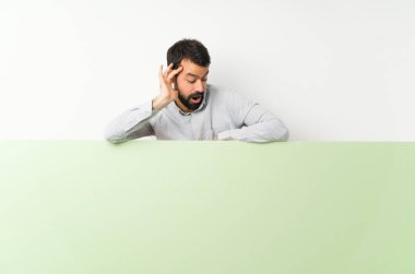 Sakallı genç yakışıklı bir adam elinde kocaman boş bir levha tutuyor.