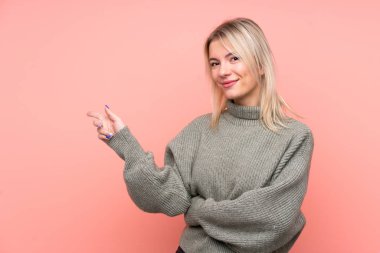 Soyutlanmış pembe arka planda genç, sarışın bir Rus kadını işaret ediyor.