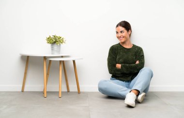 Genç bayan yerde oturmuş gülüyor.