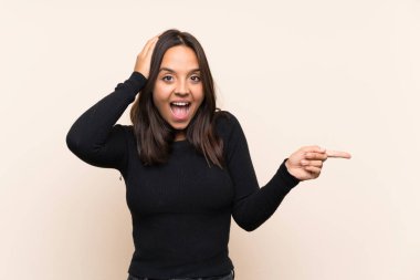 İzole edilmiş arka planda beyaz kazaklı esmer kadın şaşırdı ve parmağını yana çevirdi.