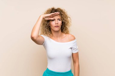 Kıvırcık saçlı, soyutlanmış bir geçmişi olan genç sarışın bir kadın bir şeye bakmak için çok uzaklara bakıyor.