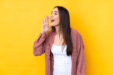 Sarı arka planda genç esmer kadın ağzı sonuna kadar açık bağırıyor.