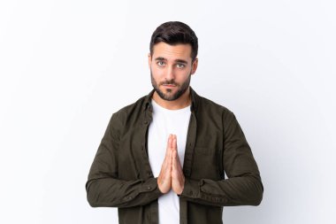 İzole edilmiş beyaz bir geçmişi olan sakallı yakışıklı genç bir adam avuç içlerini bir arada tutuyor. İnsan bir şey ister.