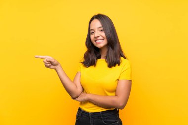 Genç esmer kız izole edilmiş arka planda parmağını yana doğru gösteriyor.