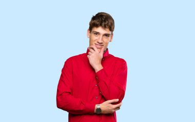 Yakışıklı genç adam soyutlanmış mavi arka planda gülüyor