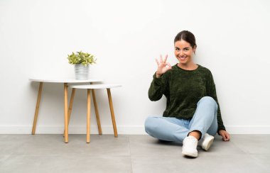 Yerde oturan genç kadın parmaklarıyla 