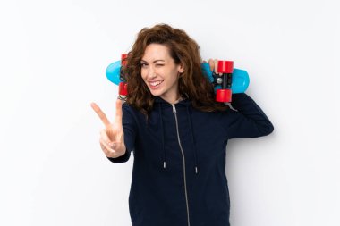 Genç ve güzel bir kadın, izole edilmiş arka planda kayıyor ve zafer jestleri yapıyor.