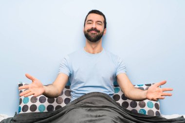 Yatakta bir adam sunuyor ve davet ediyor.