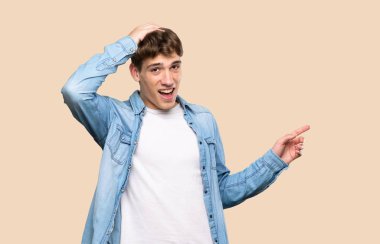 Yakışıklı genç adam şaşırdı ve izole edilmiş arka planda parmağını gösterdi.