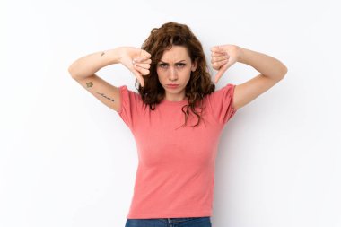 İzole edilmiş arka planda genç ve güzel bir kadın baş parmağını aşağı gösteriyor.