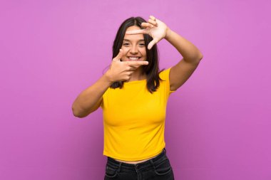 Genç esmer kız izole edilmiş arka planda yüzünü odaklıyor. Çerçeve sembolü