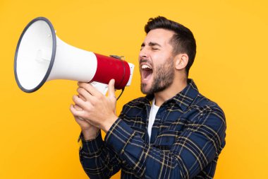 Sarı arka planda sakallı yakışıklı genç adam megafondan bağırıyor.